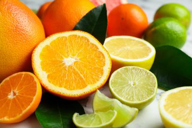 Beyaz mermer masada farklı olgun narenciye meyveleri, yakın plan.