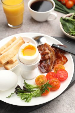 Gri masada servis edilen kaynamış yumurta ve pastırmalı lezzetli bir kahvaltı.