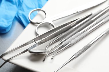 Tepside farklı diş aletleri ve masadaki tıbbi eldivenler, yakın plan.