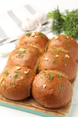 Beyaz masada sarımsaklı taze çörekler ve dereotlar, yakın plan.