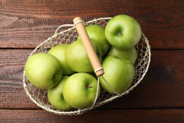 Ahşap masada metal sepetin içinde lezzetli yeşil elmalar.