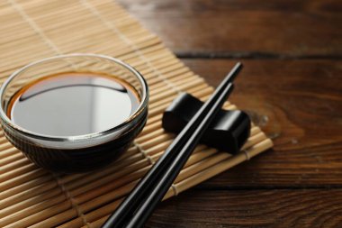 Soya sosu kasede ve çubuklar ahşap masada, yakın plan.