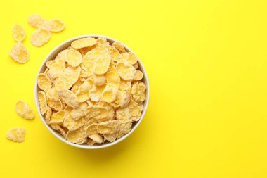 Sarı arka planda kasede lezzetli mısır gevrekleri, üst manzara. Metin için boşluk