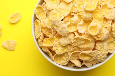 Sarı arka planda kasede lezzetli mısır gevrekleri, üst manzara.