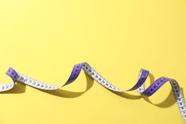 Sarı arkaplanda bir mezura, üst görünümde.