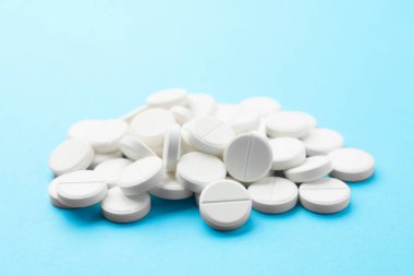 Açık mavi arka planda haplar yığını, yakın plan