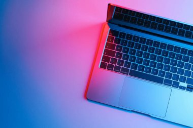 Neon lambalı modern dizüstü bilgisayar, ışık masası, üst manzara. Metin için boşluk