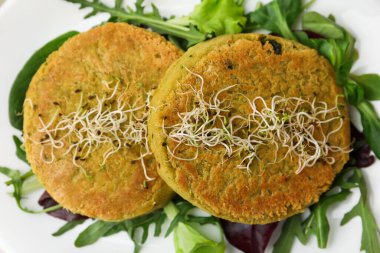 Lezzetli vejetaryen köfteler, mikro yeşillikler ve tabakta salata, yakın plan.