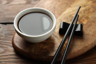 Soya sosu kasede ve çubuklar ahşap masada, yakın plan.