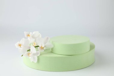 Ürün için şık bir sunum. Podyumlar ve beyaz arkaplanda güzel orkideler, yakın plan