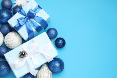 Noel mücevherleri ve açık mavi arka planda hediye kutuları, düz yatış. Metin için boşluk