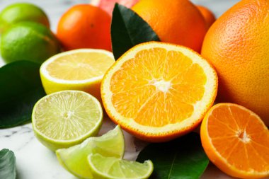 Beyaz mermer masada farklı olgun narenciye meyveleri, yakın plan.