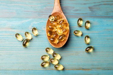 Mavi ahşap masada altın jelatin kapsüllü kaşık, düz yatıyordu.