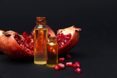 Esaslı yağ ve nar şişeleri koyu arka planda, yakın plan. Metin için boşluk