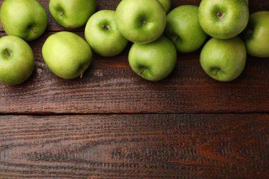 Tahta masanın üzerinde yeşil elmalar, düz bir şekilde yatıyordu. Metin için boşluk