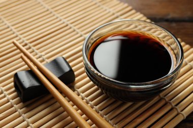 Soya sosu kasede ve çubuklar ahşap masada, yakın plan.