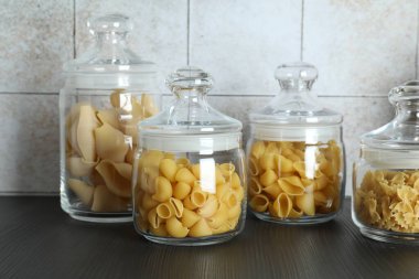 Ahşap raftaki kavanozlarda farklı türde makarna.