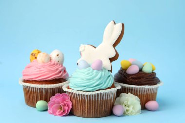 Açık mavi arkaplanda Paskalya dekoru olan lezzetli kekler, yakın plan.