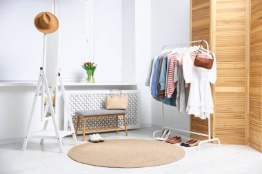 Farklı şık kıyafetler askıda, çantalarda, şapkada ve ayakkabılarda asılı.