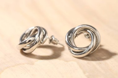 Açık arkaplanda güzel gümüş küpeler, yakın plan.