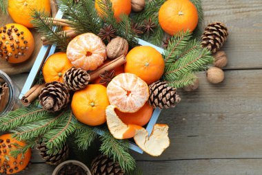 Olgun mandalinalar, baharatlar, cevizler, köknar ağacı dalları ve tahta masadaki koniler, düz yataklar. Metin için boşluk