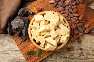 Organik kakao yağı, çikolata parçaları, fasulye ve yeşil yapraklar ahşap masa, üst görünüm