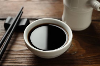 Soya sosu ve yemek çubukları ahşap masada, yakın plan.