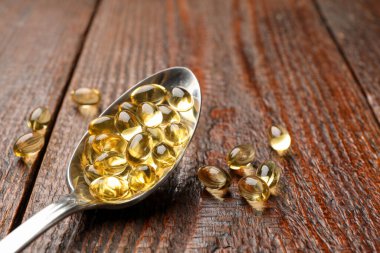 Tahta masada kaşıkta altın jelatin kapsüller, yakın plan. Metin için boşluk