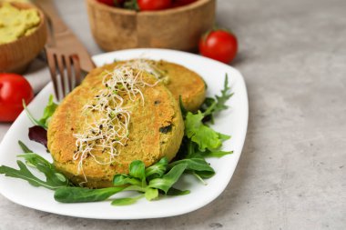 Mikroyeşillikli lezzetli vejetaryen köfteler ve gri masada salata, yakın plan.