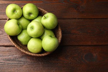 Tahta masadaki hasır sepetin içinde lezzetli yeşil elmalar, üst manzara. Metin için boşluk