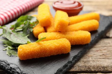 Lezzetli kızarmış peynir çubukları, yeşil ve ketçap ahşap masada, yakın plan.