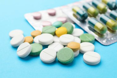 Açık mavi arka planda birçok farklı hap, yakın plan