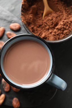 Bardakta nefis kakao, fasulye ve pudra koyu gri masada, düz uzanmış