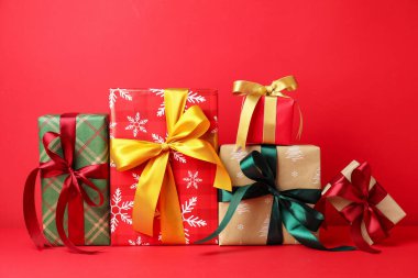 Kırmızı arka planda birçok süslü Noel hediyeleri