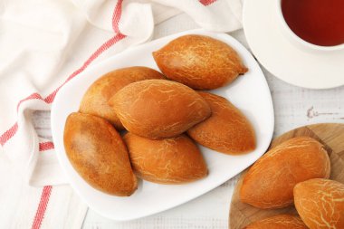 Beyaz ahşap masada çay ile servis edilen nefis fırınlanmış köfteler.