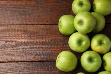 Tahta masanın üzerinde yeşil elmalar, düz bir şekilde yatıyordu. Metin için boşluk