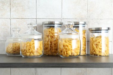 Ahşap raftaki kavanozlarda farklı türde makarna.