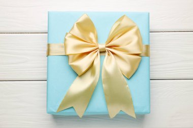 Beyaz ahşap masa üzerinde fiyonklu güzel bir hediye kutusu.
