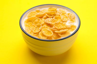 Sarı masada sütlü lezzetli mısır gevrekleri, yakın plan.