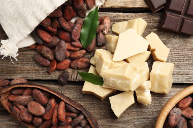 Organik kakao yağı, fasulye ve çikolata parçaları ahşap masada, düz yerde.