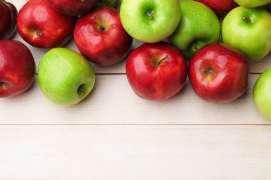 Taze kırmızı ve yeşil elmalar açık ahşap masada, düz yerde. Metin için boşluk