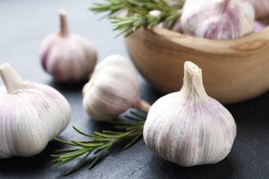 Siyah masada taze sarımsak soğanı ve biberiye, yakın plan.