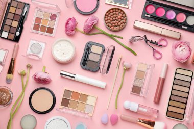 Farklı makyaj ürünleri ile bahar kompozisyonu ve pembe arka planda çiçekler, düz yatıyordu