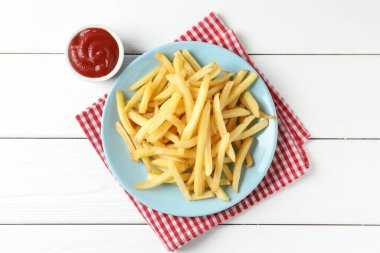 Beyaz ahşap masada ketçaplı patates kızartması.