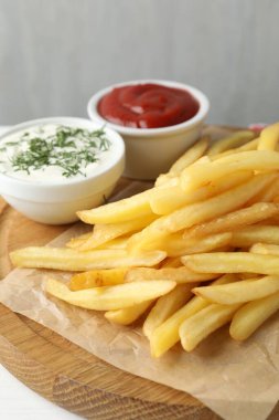 Beyaz ahşap masada soslu patates kızartması, yakın plan.