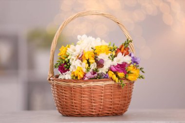 Sepetteki güzel frezya çiçekleri bulanık arka plana karşı ışık masasının üzerinde