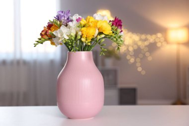 Vazoda güzel frezya çiçekleri beyaz masada bulanık arka planda.