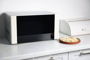 Modern mikrodalga fırın ve mutfak tezgahında tavuklu pilav, yakın plan.