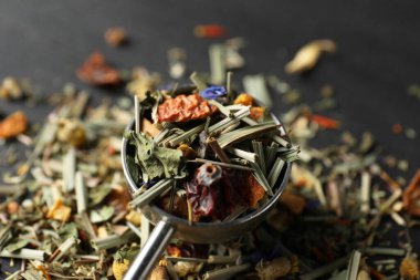 Koyu masa üzerinde kurutulmuş bitki çayı yaprakları ile kepçe, yakın çekim