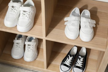 Raf ünitesinde farklı stil çocuk ayakkabıları var. Kapalı, yakın çekim.